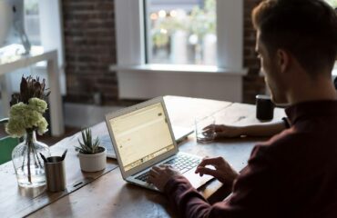man operating laptop on top of table